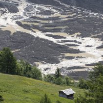epa12148726 Water from the Lonza river flows over the mud and stone, after the formation of a lake on the last houses of the village of Blatten, Switzerland, 01 June 2025. A large part of the Blatten village, located in the Loetschental Valley in the canton of Valais, was buried under masses of ice, mud, and rock on 28 May after several million cubic meters of rock fell from the Kleines Nesthorn mountain above the village, resulting in the collapse of the Birch Glacier. EPA/CYRIL ZINGARO