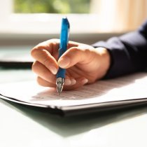Close-up Of A Businesswoman's Hand Filling Contract Form